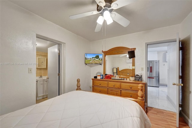 bedroom featuring ceiling fan, stainless steel refrigerator, light hardwood / wood-style floors, ensuite bath, and sink