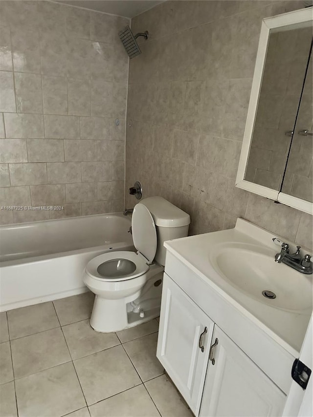 full bathroom featuring vanity, toilet, tiled shower / bath combo, and tile walls