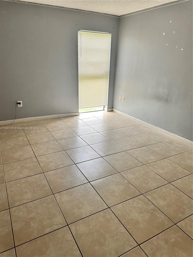 tiled spare room with ornamental molding and a textured ceiling