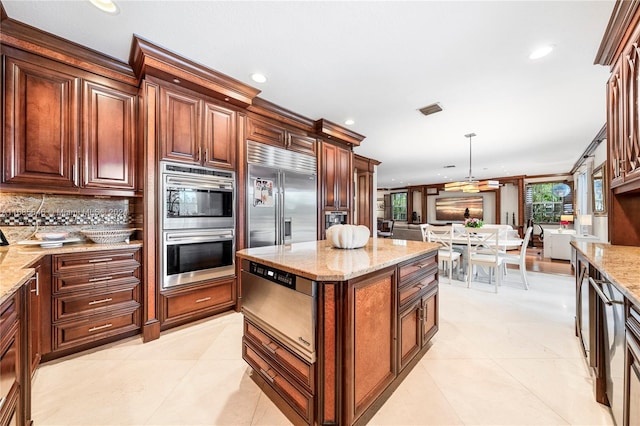 kitchen with light stone countertops, hanging light fixtures, stainless steel appliances, and tasteful backsplash