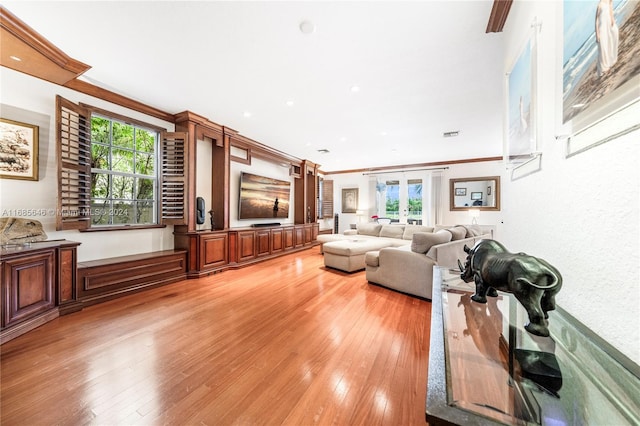 living room featuring crown molding, light hardwood / wood-style floors, and a healthy amount of sunlight