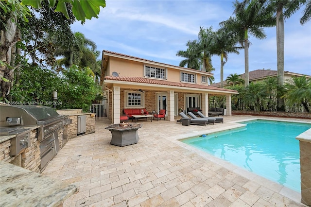 rear view of house with a patio area, an outdoor living space with a fire pit, a fenced in pool, and exterior kitchen