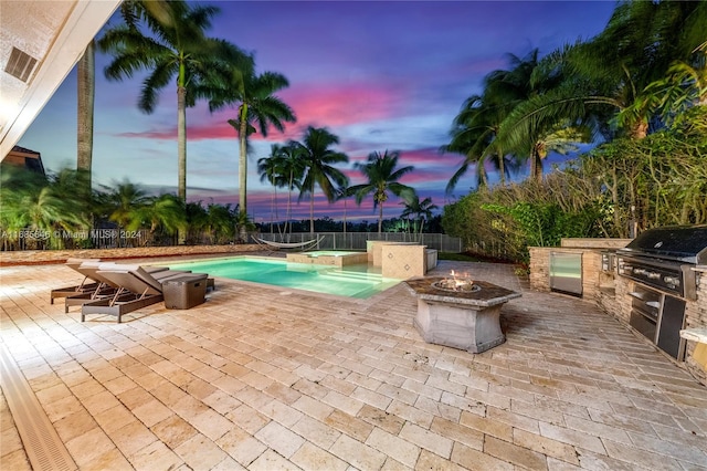 pool at dusk featuring a patio area, area for grilling, a fire pit, and grilling area