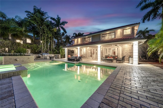 back house at dusk featuring a swimming pool with hot tub, an outdoor hangout area, a patio, and ceiling fan