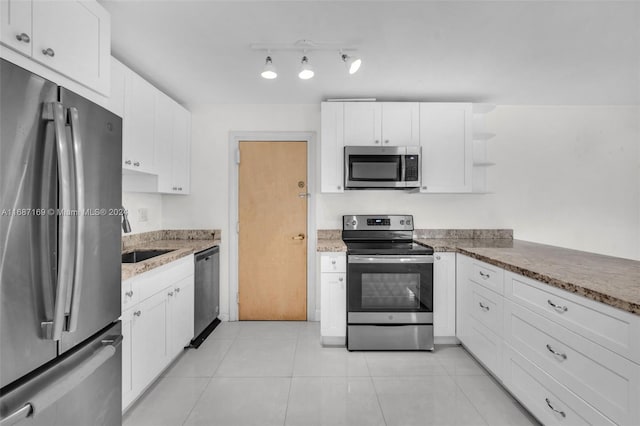 kitchen featuring stainless steel appliances, stone counters, sink, light tile patterned floors, and white cabinetry