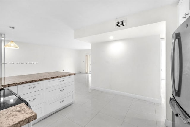 kitchen featuring pendant lighting, stainless steel refrigerator, light tile patterned floors, and white cabinets