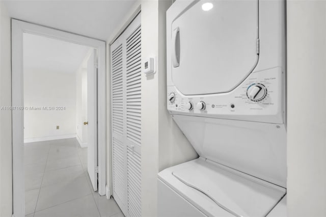 laundry room with light tile patterned floors and stacked washer / drying machine