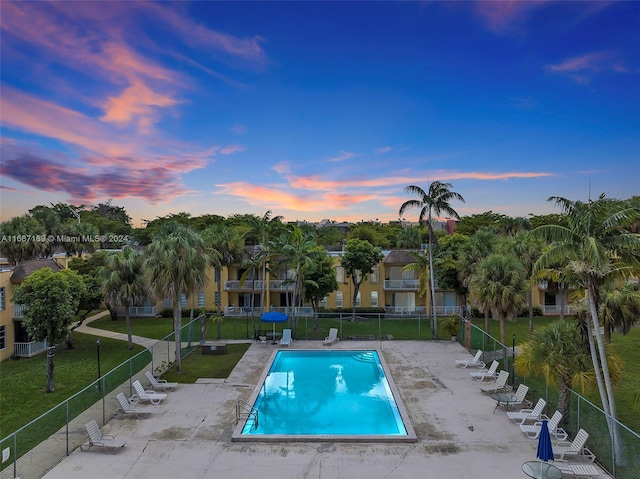 pool at dusk with a yard and a patio area