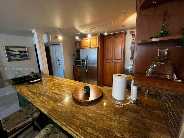 kitchen featuring dark stone countertops, ornate columns, stainless steel appliances, and kitchen peninsula