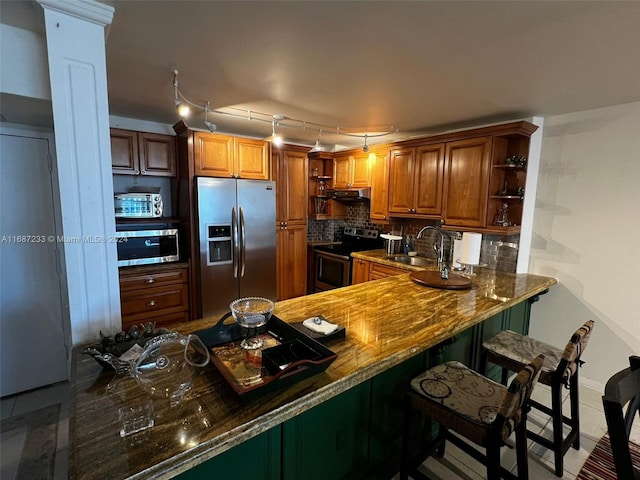 kitchen with kitchen peninsula, decorative backsplash, stainless steel appliances, and sink