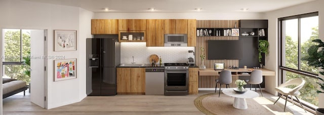 kitchen with appliances with stainless steel finishes, sink, light wood-type flooring, and backsplash