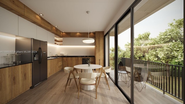 kitchen with white cabinetry, light wood-type flooring, fridge with ice dispenser, and hanging light fixtures