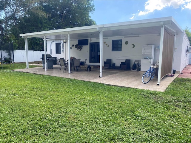 rear view of property with a yard, a trampoline, a patio area, and ceiling fan