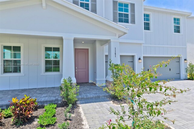 doorway to property with covered porch and a garage