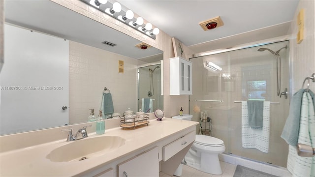 bathroom featuring toilet, vanity, tile patterned floors, and a shower with door