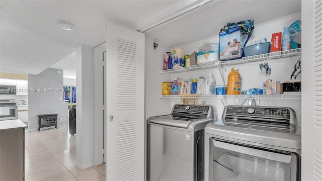 clothes washing area featuring washing machine and dryer and light tile patterned flooring