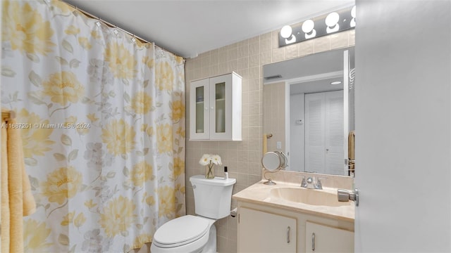 bathroom featuring toilet, a shower with shower curtain, vanity, and tile walls