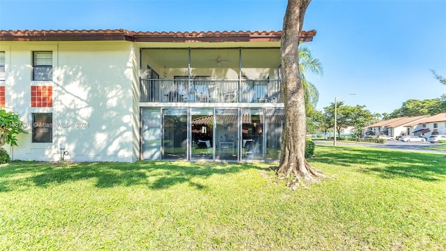 rear view of property featuring a balcony and a lawn