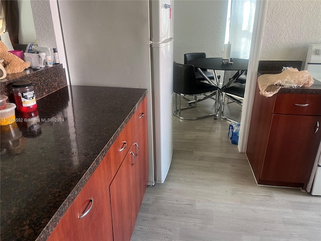 kitchen with light hardwood / wood-style flooring and dark stone counters