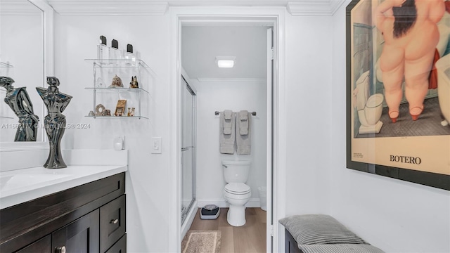 bathroom featuring a shower with shower door, toilet, vanity, hardwood / wood-style flooring, and ornamental molding