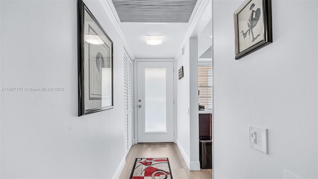 corridor with ornamental molding and light wood-type flooring