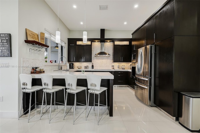 kitchen featuring backsplash, wall chimney exhaust hood, appliances with stainless steel finishes, and decorative light fixtures