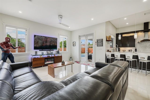 tiled living room featuring ceiling fan, sink, and plenty of natural light