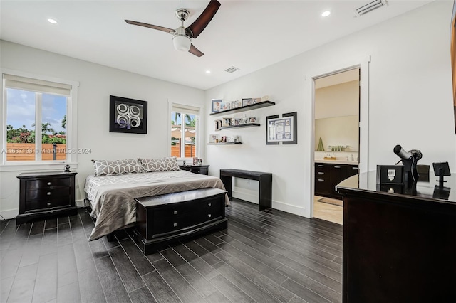 bedroom featuring ensuite bath, dark wood-type flooring, and ceiling fan