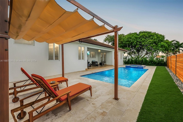 pool at dusk featuring an in ground hot tub and a patio area