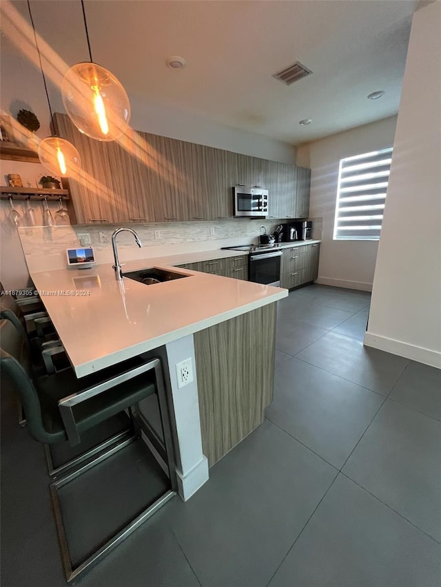 kitchen with decorative backsplash, kitchen peninsula, sink, pendant lighting, and appliances with stainless steel finishes