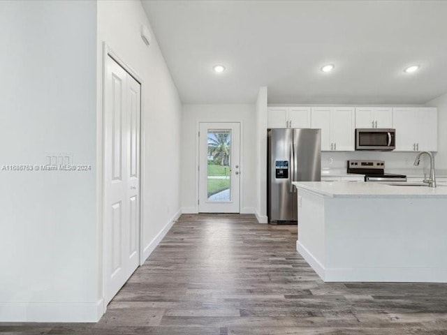 kitchen with sink, white cabinets, stainless steel appliances, and hardwood / wood-style flooring