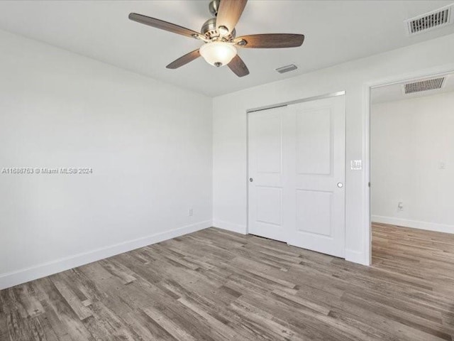 unfurnished bedroom featuring hardwood / wood-style floors, a closet, and ceiling fan