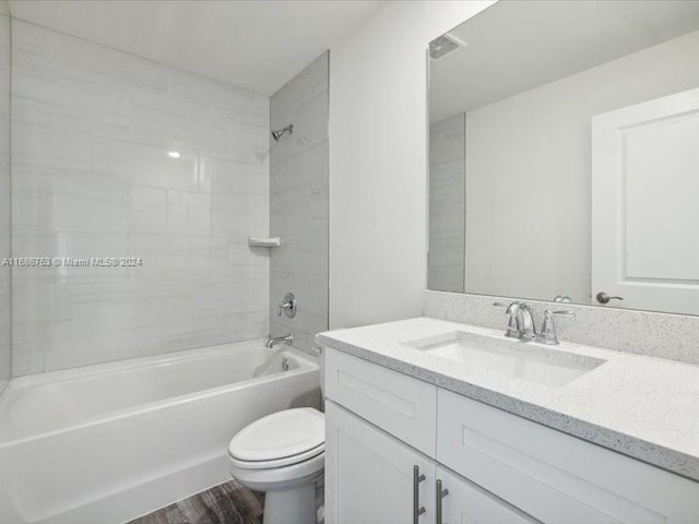 full bathroom with toilet, tiled shower / bath combo, hardwood / wood-style flooring, and vanity