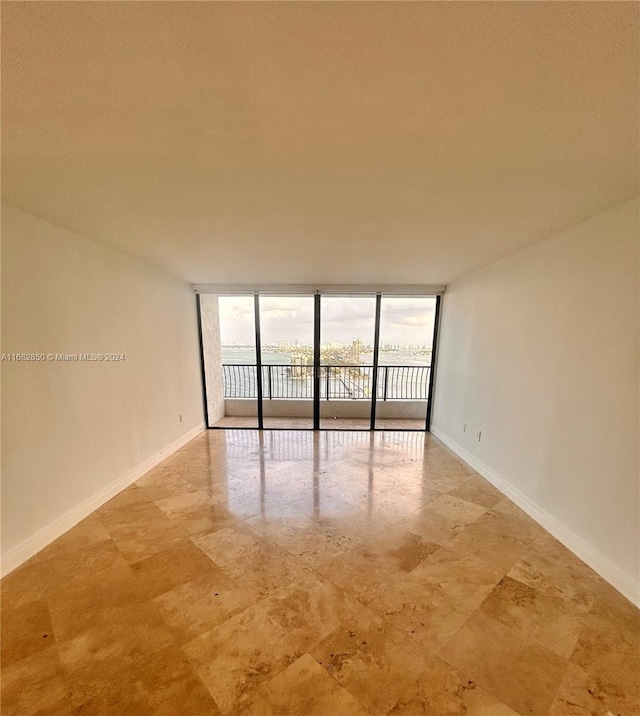 unfurnished room featuring a textured ceiling, a healthy amount of sunlight, and floor to ceiling windows