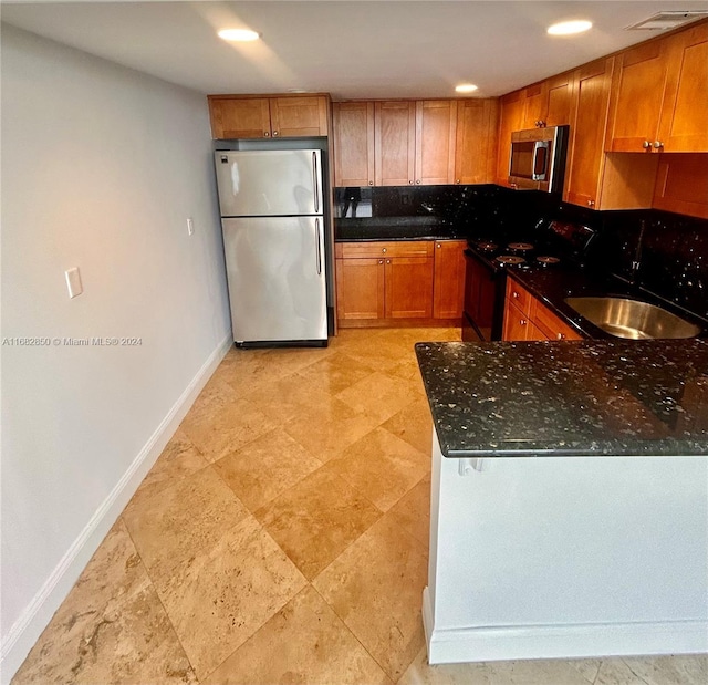 kitchen with stainless steel appliances, dark stone counters, and sink