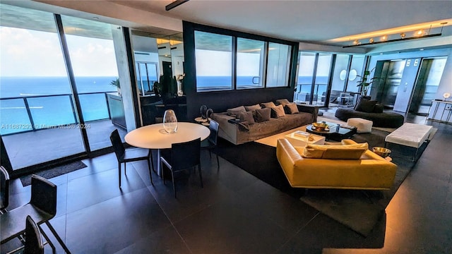 living room featuring tile patterned flooring, floor to ceiling windows, and a water view