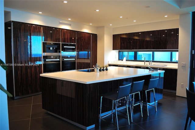 kitchen featuring a breakfast bar, a center island, dark tile patterned floors, and black electric cooktop