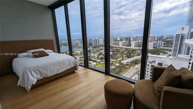 bedroom featuring multiple windows, floor to ceiling windows, and wood-type flooring