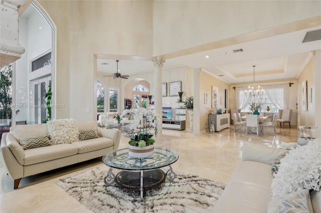 living room featuring a high ceiling, ceiling fan with notable chandelier, and a healthy amount of sunlight