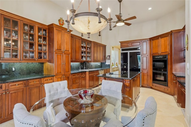 kitchen with a high ceiling, sink, black appliances, decorative light fixtures, and tasteful backsplash