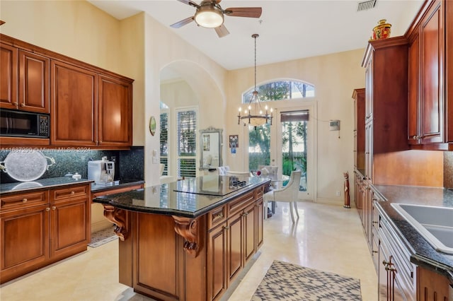 kitchen with decorative backsplash, a kitchen island, dark stone countertops, black appliances, and pendant lighting