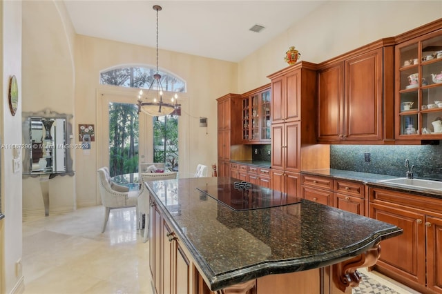 kitchen with black electric stovetop, sink, a center island, pendant lighting, and decorative backsplash