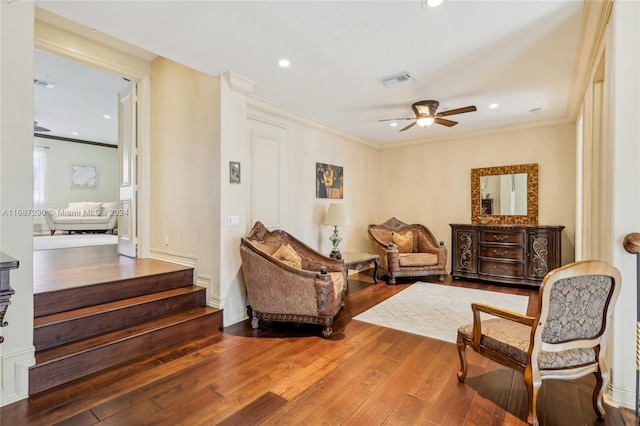 living area with hardwood / wood-style floors, crown molding, and ceiling fan