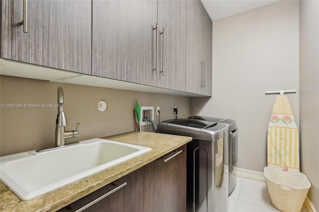 clothes washing area with sink, independent washer and dryer, light tile patterned floors, and cabinets