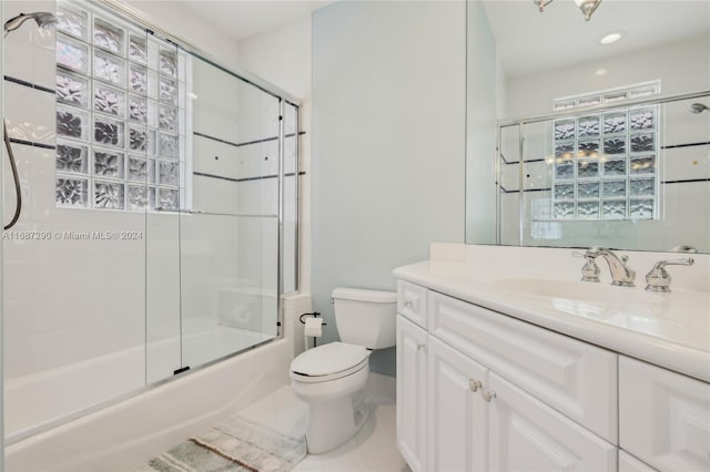 full bathroom featuring vanity, bath / shower combo with glass door, toilet, and tile patterned flooring