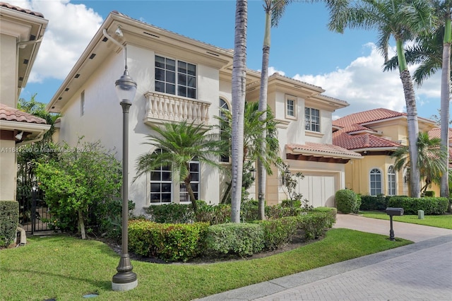 mediterranean / spanish-style house with a garage and a front lawn