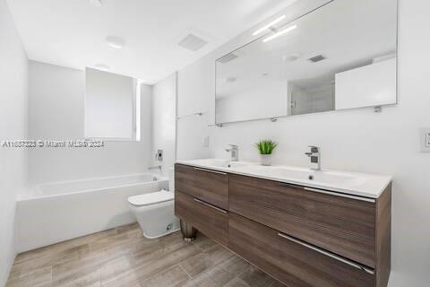 full bathroom featuring vanity, toilet, wood-type flooring, and bathing tub / shower combination