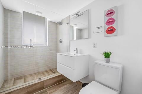 bathroom with hardwood / wood-style floors, vanity, an enclosed shower, and toilet