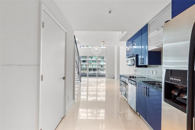 kitchen featuring light tile patterned floors, appliances with stainless steel finishes, blue cabinets, and backsplash