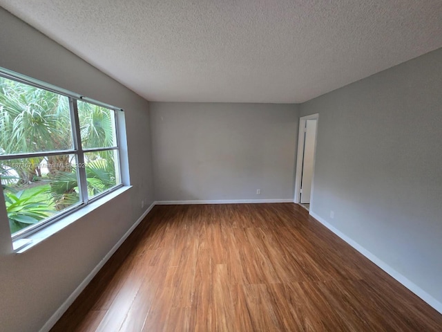 unfurnished room with a textured ceiling and wood-type flooring